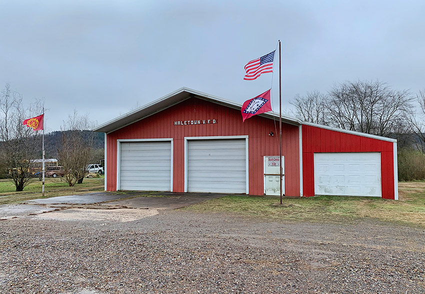 Red metal building with three garage bay doors and flagpoles