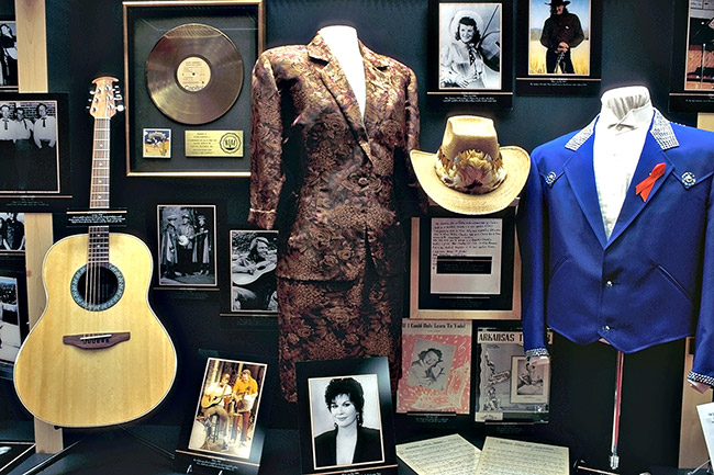Music memorabilia with guitar stage clothes and photographs in display case