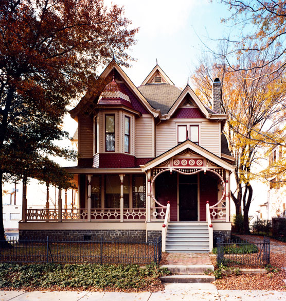 Two-story house with ornate porch and autumn foliage
