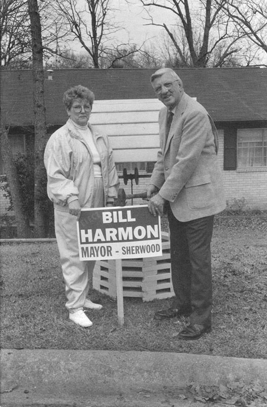 White woman and white man standing beside political yard sign