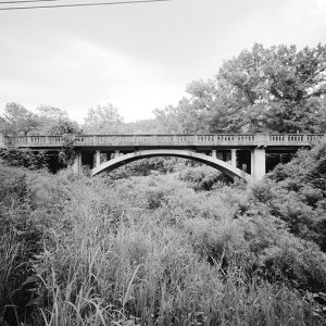 Concrete arch bridge over tree covered creek