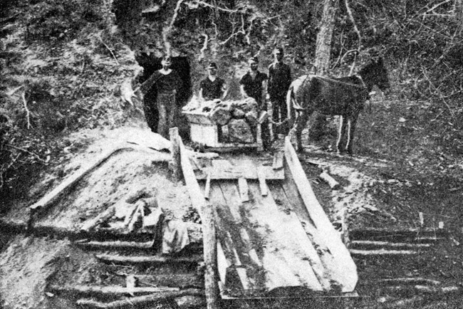 White miners and horse at entrance of mine with cart filled with coal and ramp