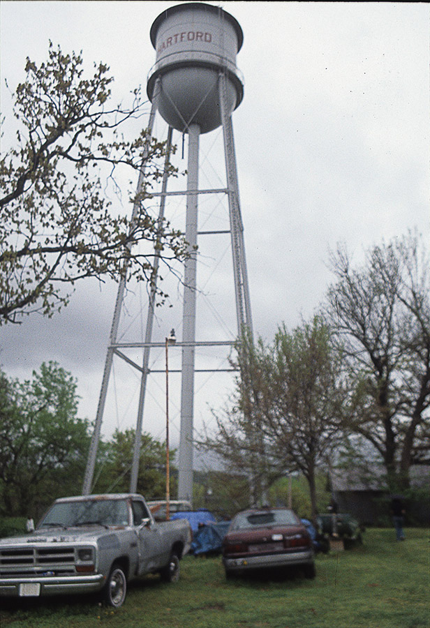 Car and truck parked under water tower