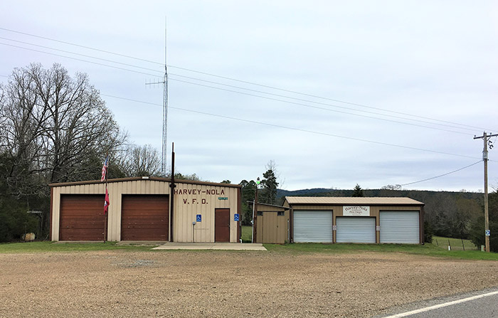 Two metal buildings with garage bay doors on gravel parking lot