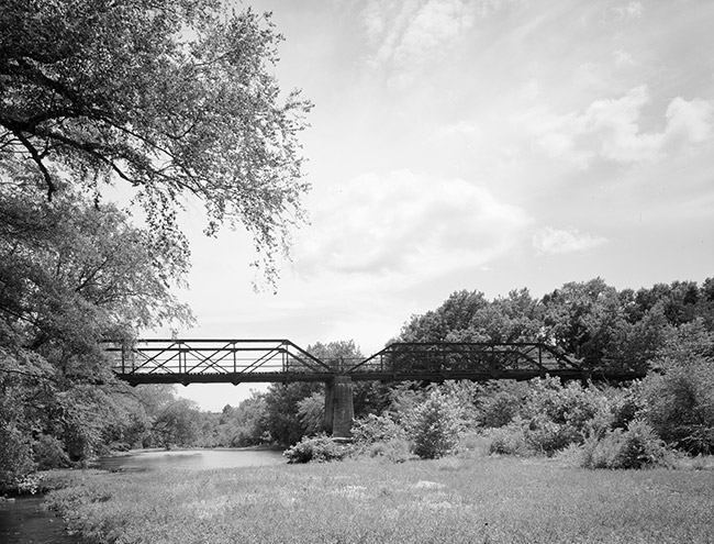 Steel truss bridge with concrete supports over creek