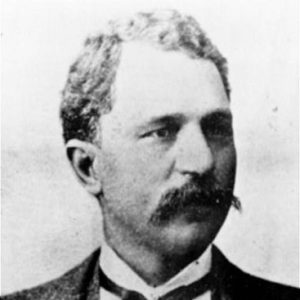 African-American man with short hair and a mustache wearing a suit and bow tie