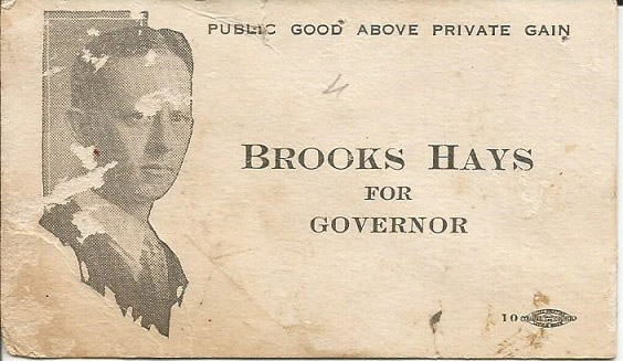 White man in suit and tie on wrinkled card with text