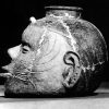 Pot shaped like a human head with ears and face and opening at top