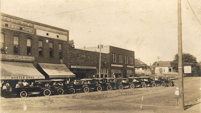 Parked cars on street outside brick store front buildings