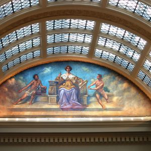 Arched glass roof with marble supports above a painting of a white man in a throne with a young white man on either side of him