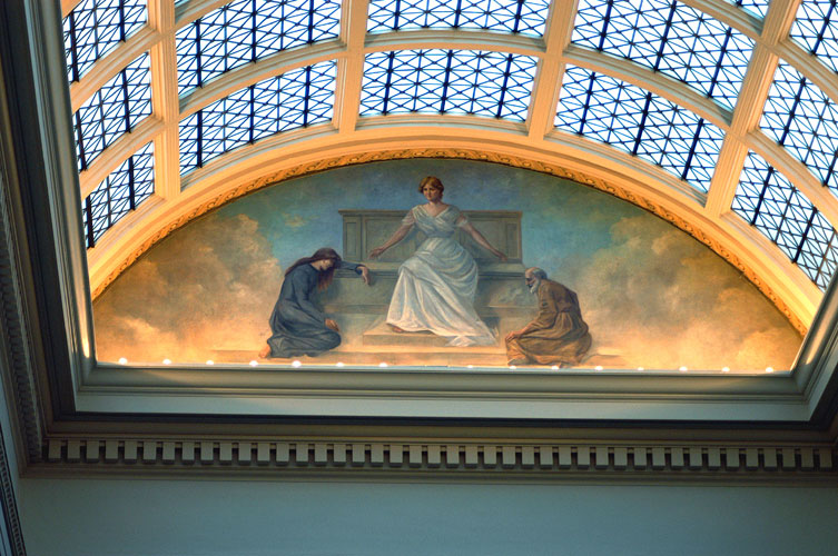 Glass roof with marble supports above a painting of a white woman in white robes with white man and woman bowing to her