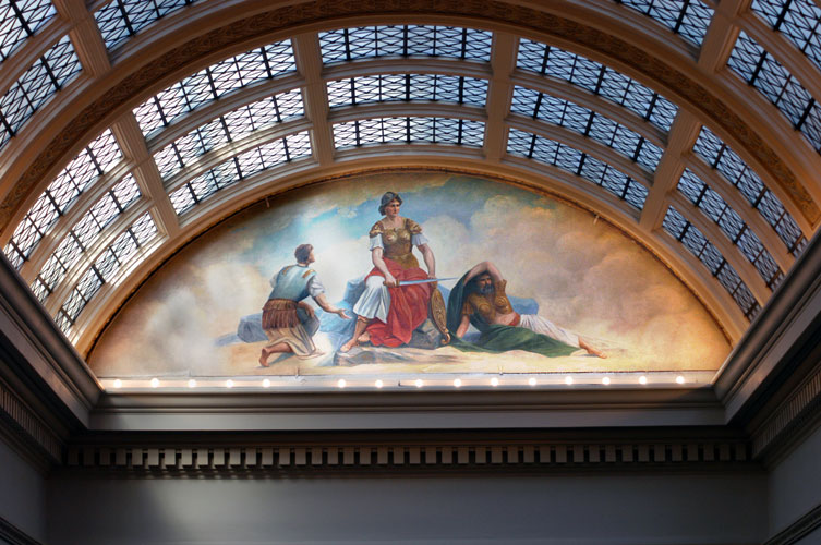 Glass roof with marble supports above a painting of a woman in armor holding sword and two white men in robes on either side of her