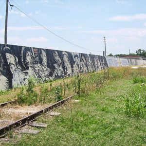 White and African-American musicians painted on cement levee wall behind railroad tracks