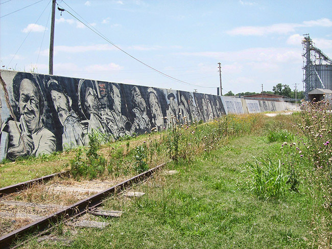 White and African-American musicians painted on cement levee wall behind railroad tracks