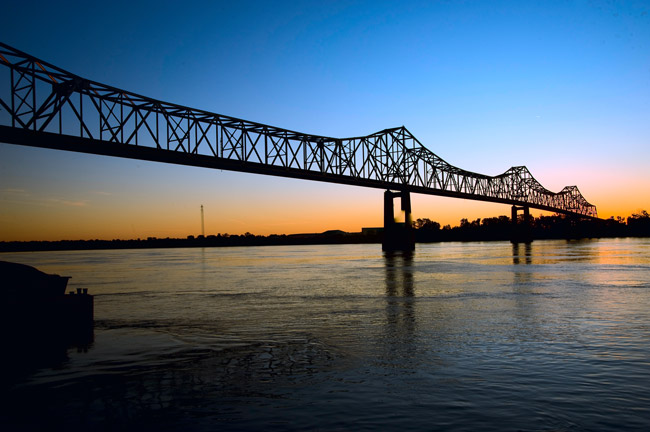 Steel cantilever bridge over river at sunset