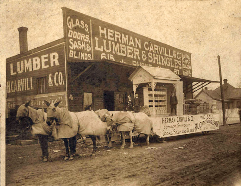 Horse drawn parade float outside "Herman Carvill and company lumber and shingles" store