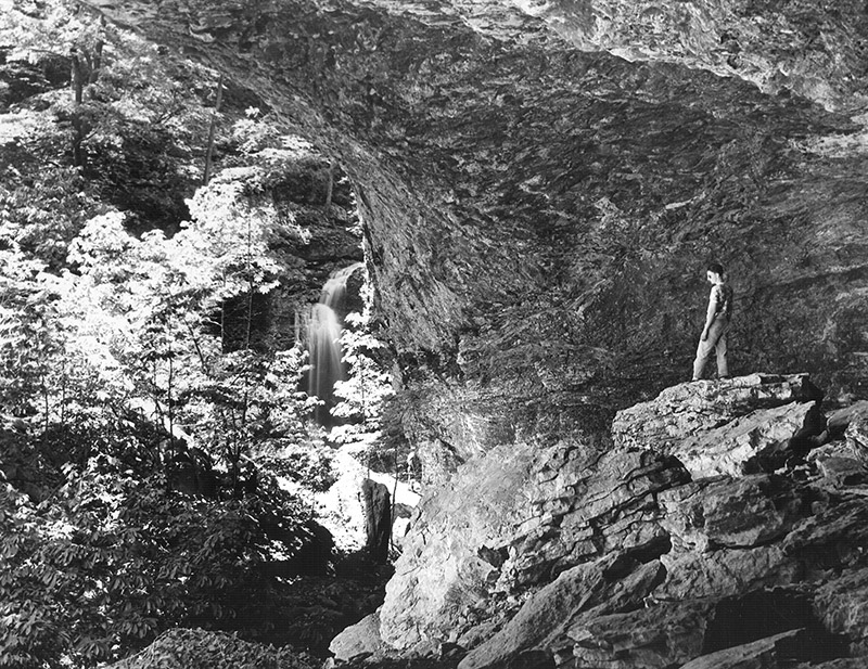 Man standing on rock outcrop above waterfall