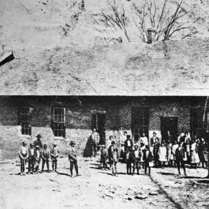 African-American children and faculty standing outside single-story brick building