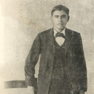 Young Cherokee man in suit standing next to a chair