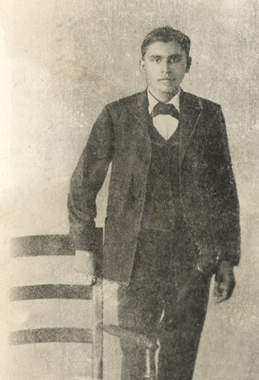 Young Cherokee man in suit standing next to a chair