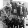 Two white men in hats with three dogs
