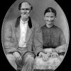 Old white man with beard sitting next to old white woman in dress in oval frame