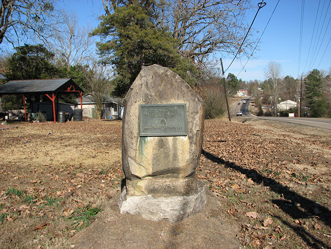 Historical marker plaque on large rock in yard next to street