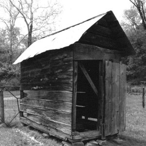 Narrow wooden outbuilding with metal roof on farm