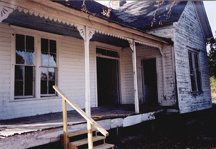 Abandoned house with covered porch and white siding