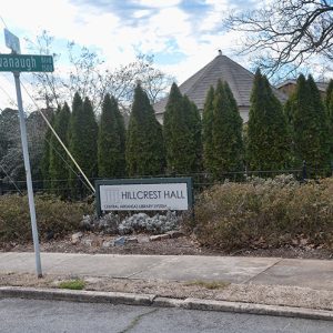 Building with gazebo visible behind trees and Hillcrest Hall sign from street
