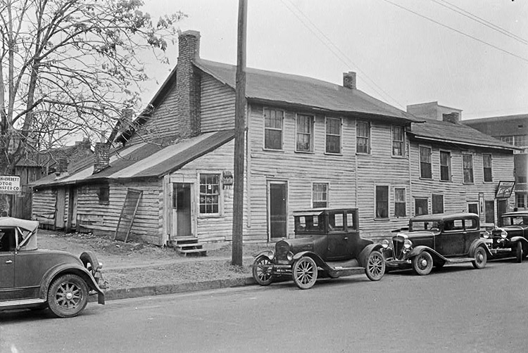 Cars parked outside two-story building with brick chimney