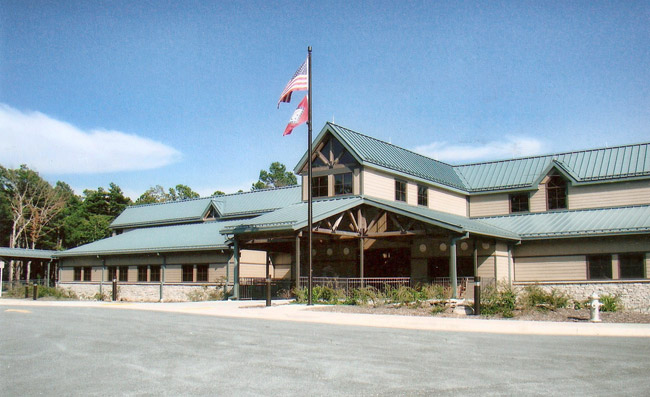 Two-story building with green roof and state and American flags