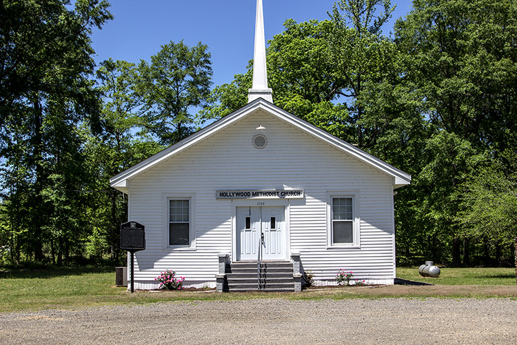 Single-story church building with white siding and steeple on its roof