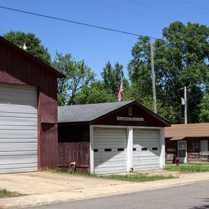 Single garage building next to double garage building next to single-story building all with wood siding