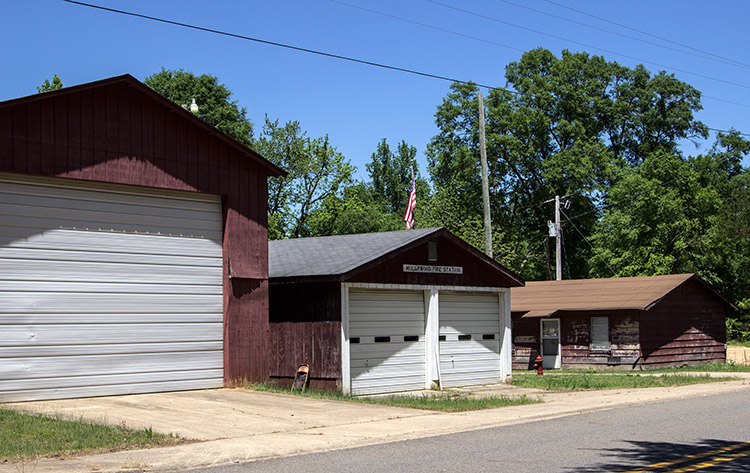 Single garage building next to double garage building next to single-story building all with wood siding