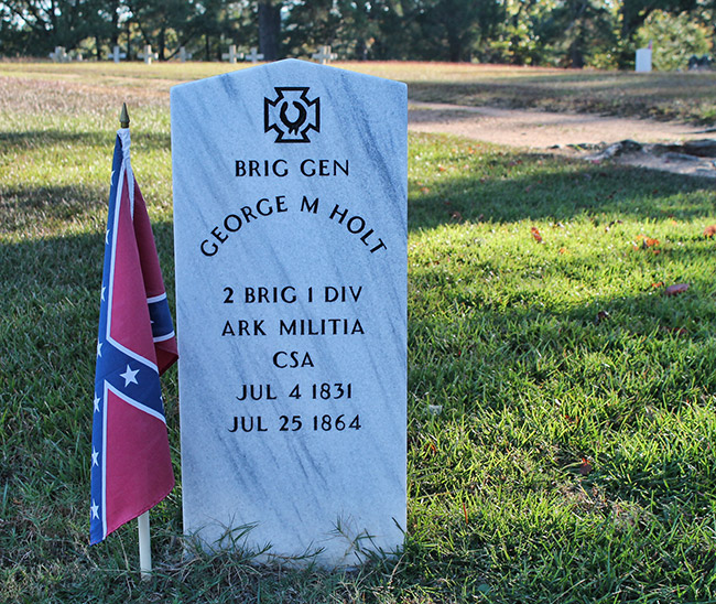 Engraved white gravestone in cemetery with Confederate Battle Flag in cemetery
