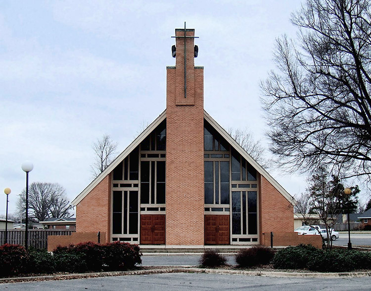 Brick A-frame church building with tower and two front entrances