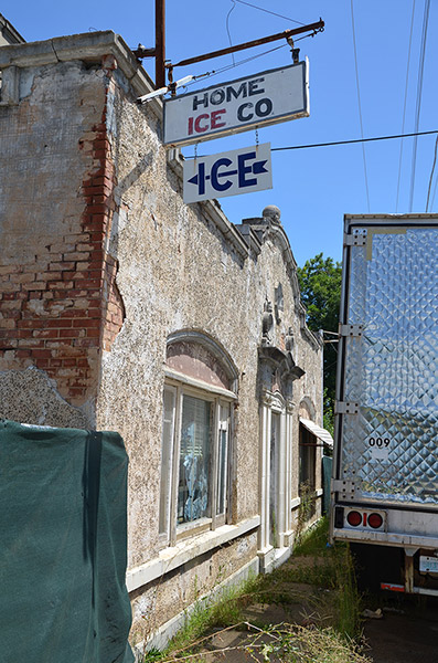Brick storefront with hanging signs and semi-tuck trailer