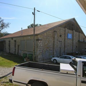 Stone building with blue sign and parking lot