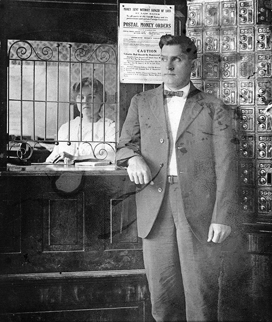 White woman working behind desk with bars and white man in suit standing in the foreground