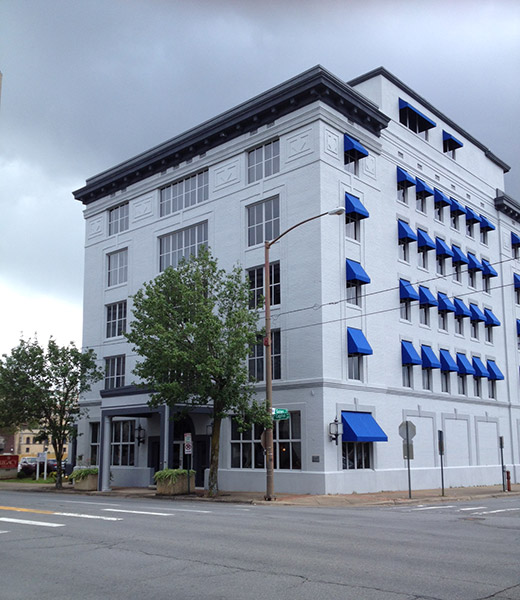 Five-story building with blue window awnings on street corner