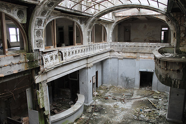 Inside abandoned two-story ornate hotel lobby with glass roof