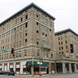 six-story buff brick hotel building on street corner with sets of columns in front