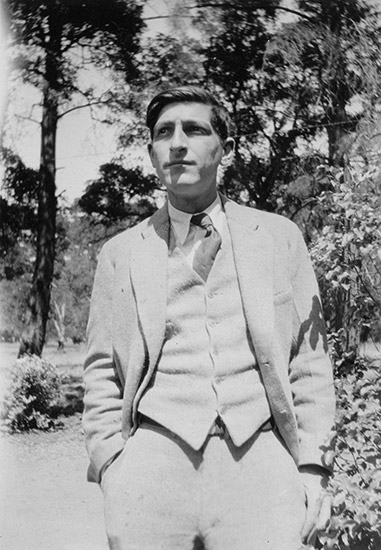 White man in suit and tie standing outdoors with his hands in his pockets