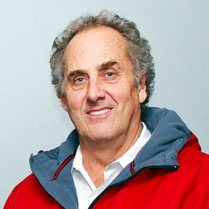 Older white man smiling in red gray and black jacket