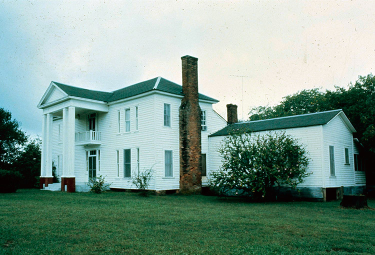 Multistory house with four columns and brick chimneys