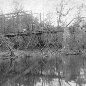 Steel truss bridge under construction over creek