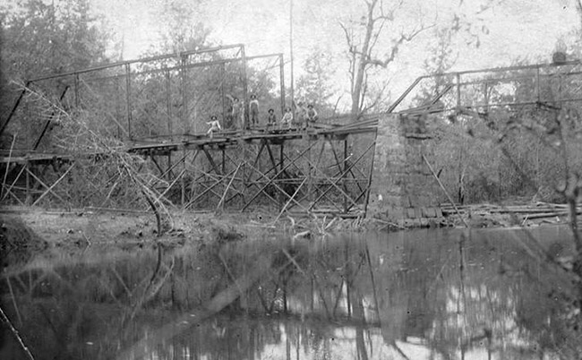 Steel truss bridge under construction over creek