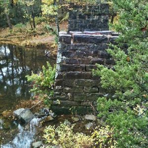 Rock bridge columns in creek with autumn trees