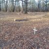 Crosses and gravestones in recently cleaned cemetery with pile of branches in its center
